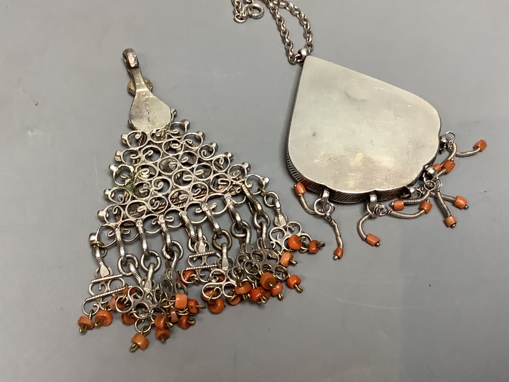 Two shaped Afghan? white metal or parcel gilt white metal, coral bead set pendants, one on a white metal chain